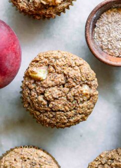 a close up photo of a peach bran muffin on a white table