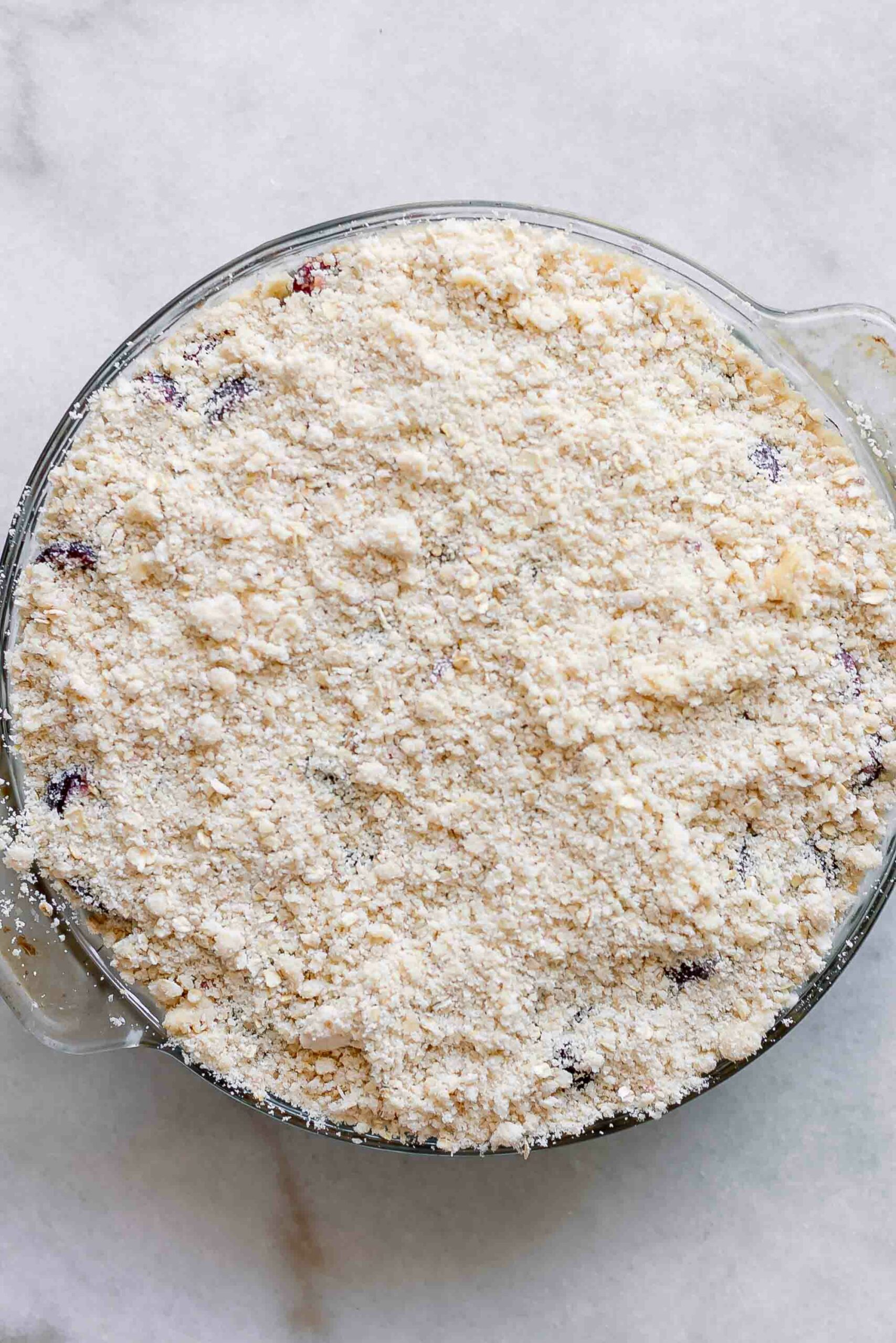 a baking dish with a cherry crisp and crumbly topping before baking 