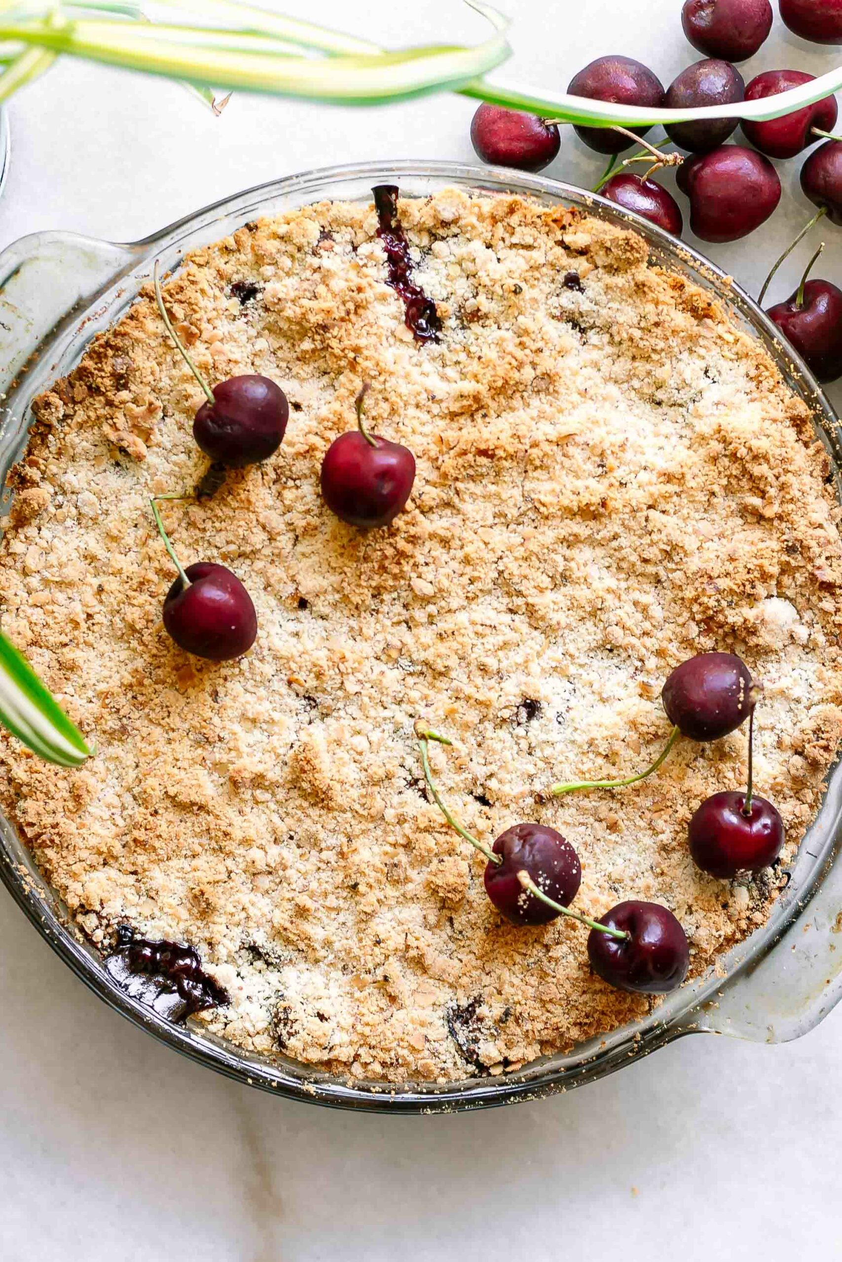 a cherry crisp baking dish topped with fresh cherries after coming out of the oven