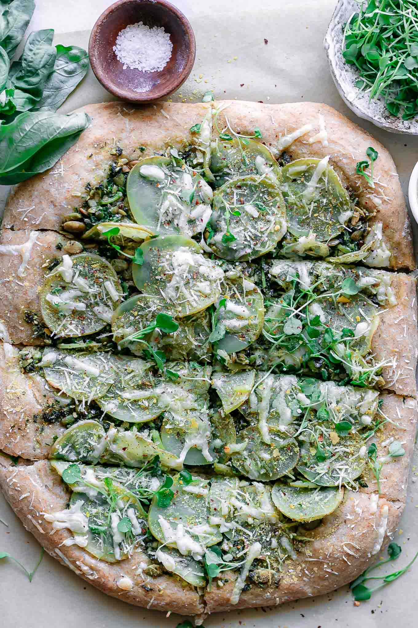 a vegan pesto potato pizza with fresh micro greens on top